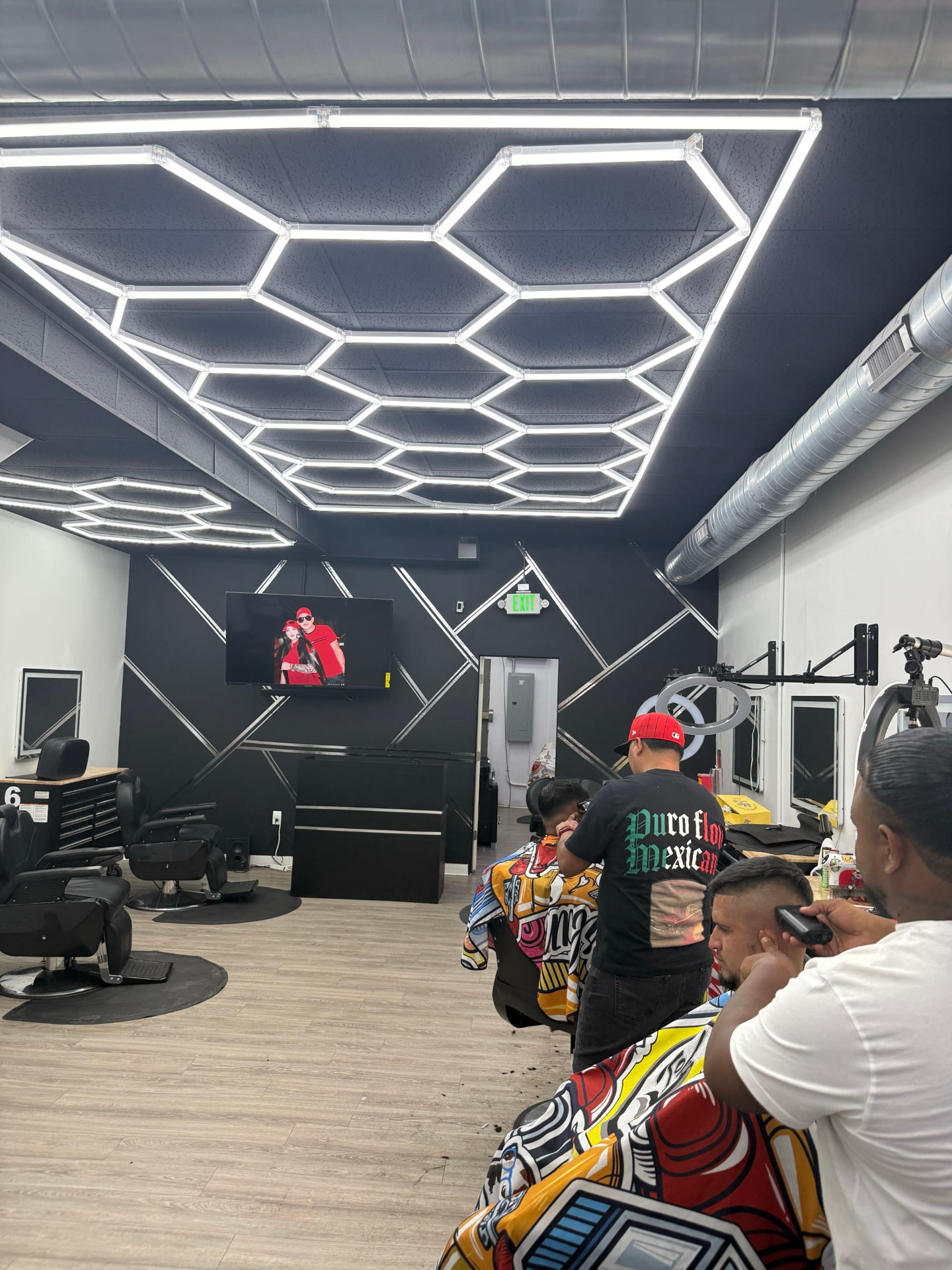 Barbers cutting hair under the hexagon lights at Don Barbas